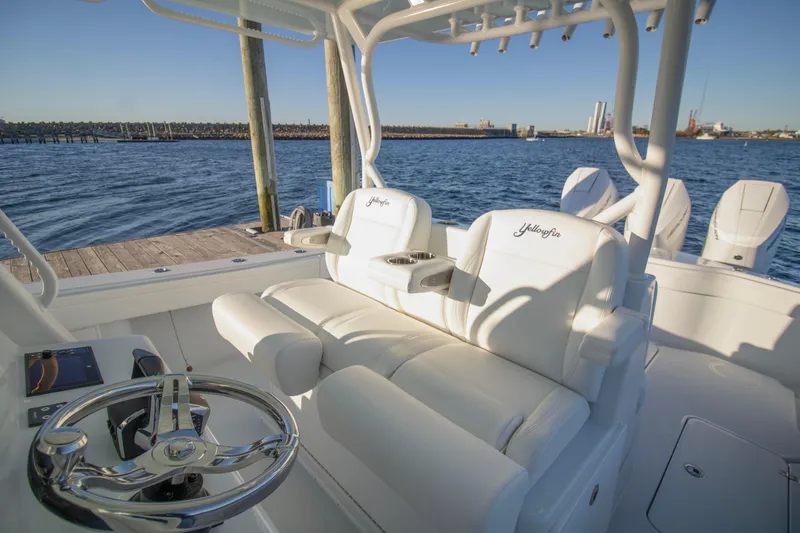 Slide: The Image of 2024 Yellowfin 39 boat interior with white seating and steering wheel, docked by the water. - 28