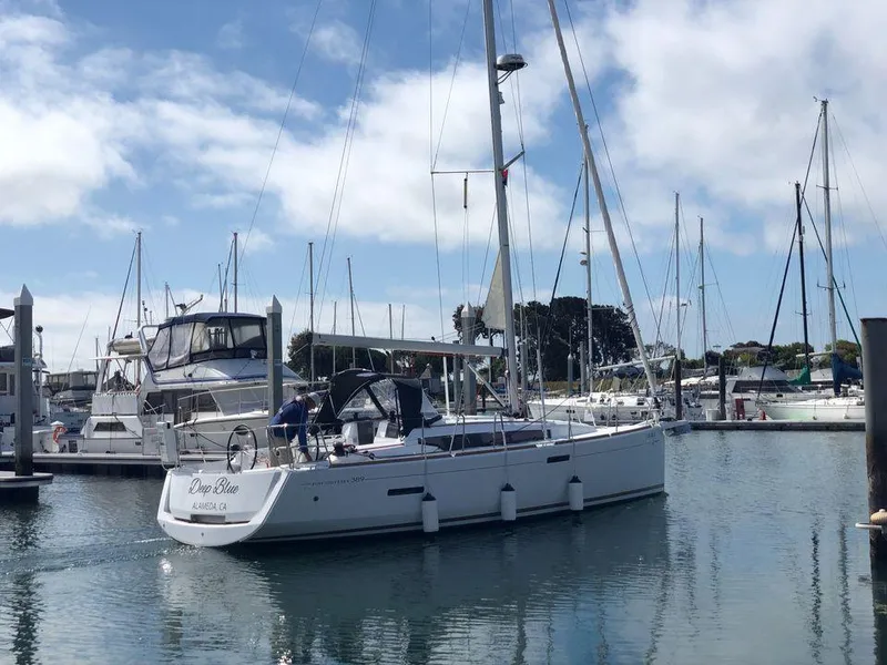 Slide: The Image of 2020 Jeanneau Sun Odyssey 389 sailboat docked in a marina under a blue sky. - 0