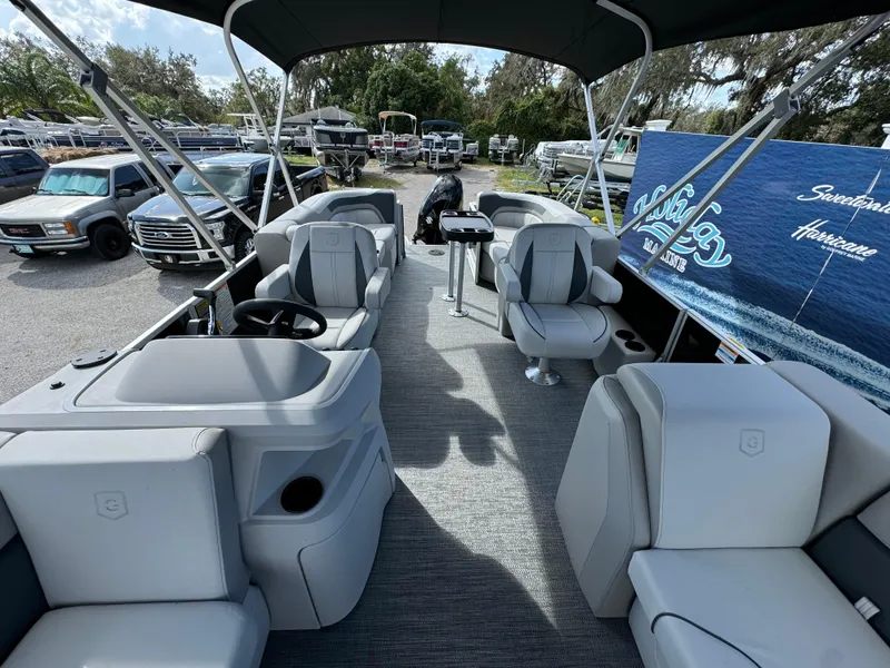 Slide: The Image of 2025 Sweetwater 2286 SB pontoon boat interior with seating and helm, parked outdoors. - 7