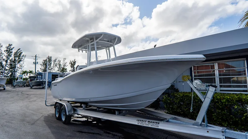Slide: The Image of 2025 Tidewater 220 CC Adventure boat on trailer, parked outdoors under cloudy sky. - 13