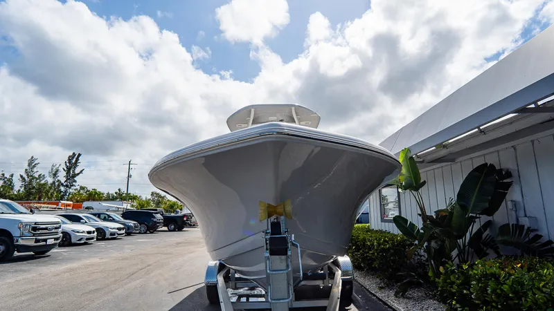 Slide: The Image of 2025 Tidewater 220 CC Adventure boat on trailer, parked outdoors under cloudy sky. - 14