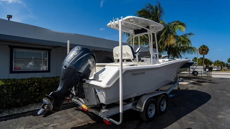 Slide: The Image of 2025 Tidewater 220 CC Adventure boat on trailer, parked near palm trees and building. - 16