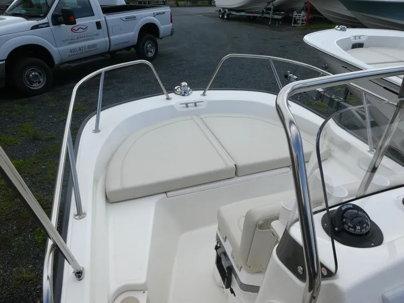 Slide: The Image of 2025 Boston Whaler 150 Montauk boat interior with cushioned seating and stainless steel railings. - 5