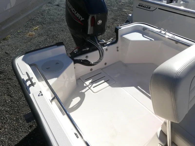 Slide: The Image of 2025 Boston Whaler 150 Montauk boat interior with Mercury engine, white seating, and clean deck. - 7