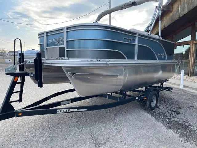 Slide: The Image of 2023 SunCatcher Select 16F pontoon boat on trailer, parked outdoors. - 2