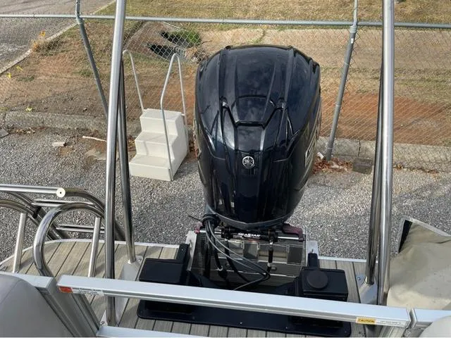 Slide: The Image of 2023 SunCatcher Select 324RC boat with powerful outboard motor, docked on gravel surface. - 11