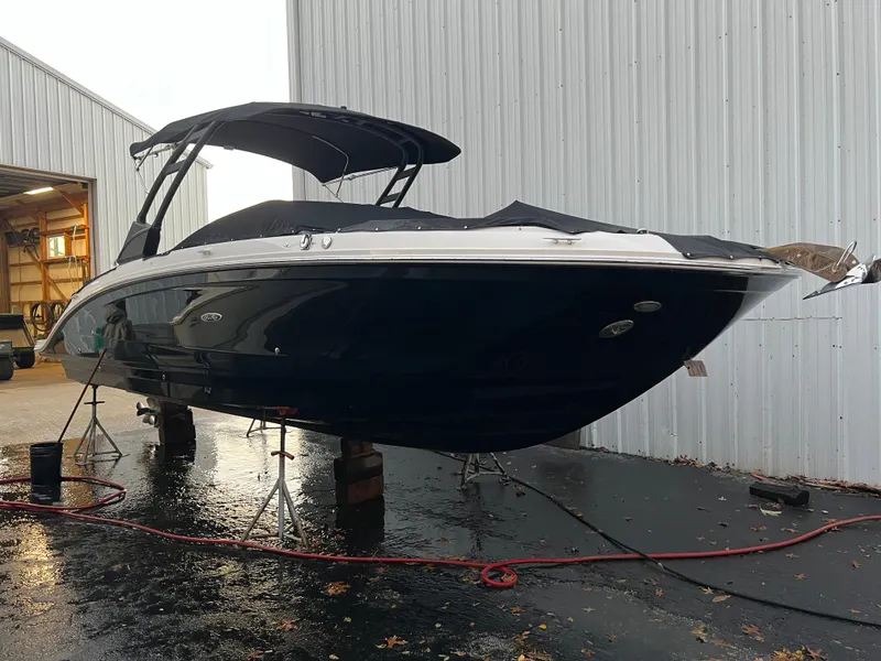 The Image of 2022 Sea Ray SDX 290 boat on stands near a metal building. - 0