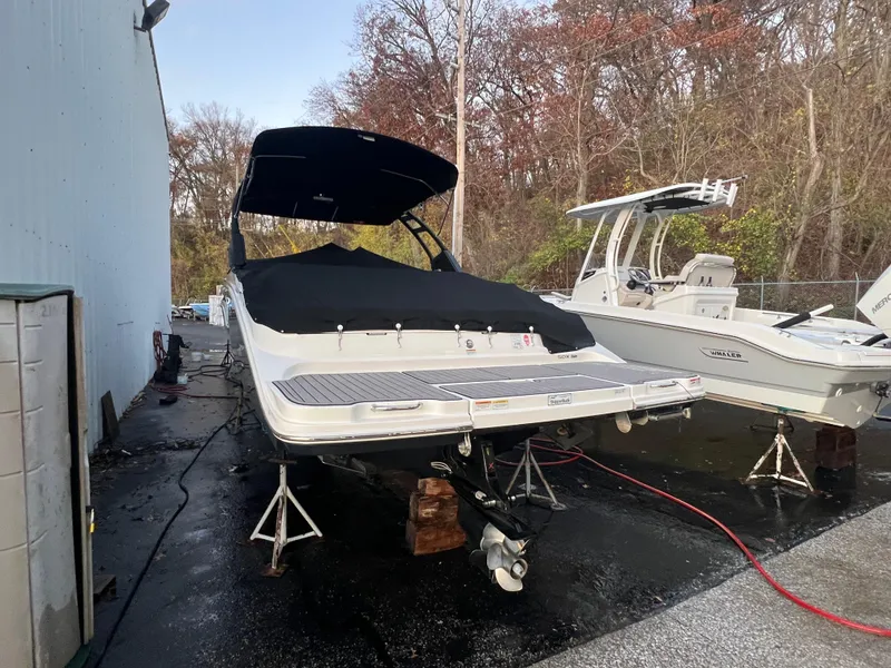 Slide: The Image of 2022 Sea Ray SDX 290 boat on stands, covered, near a building and trees. - 12