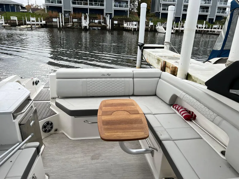 Slide: The Image of 2022 Sea Ray SDX 290 boat interior with seating and wooden table by the dock. - 3