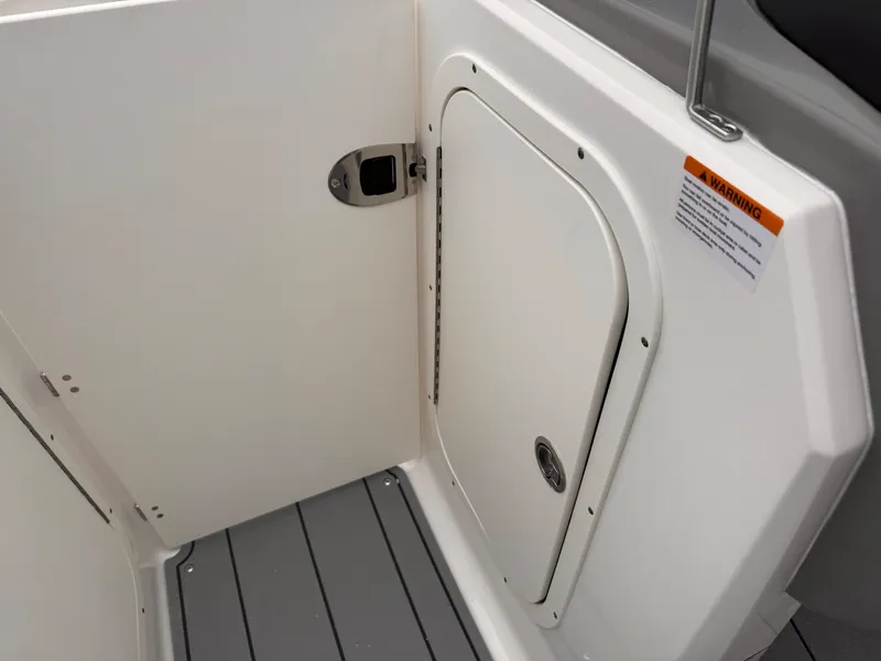 Slide: The Image of 2025 Chaparral 23 SSi OB boat interior, featuring a white storage compartment and gray flooring. - 37