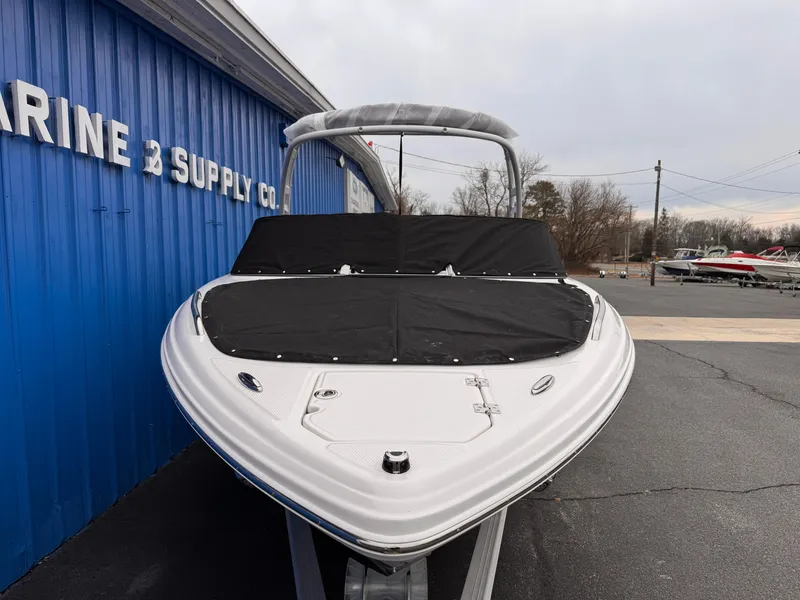 Slide: The Image of 2025 Chaparral 23 SSi OB boat with cover, parked outside a marine supply store. - 40