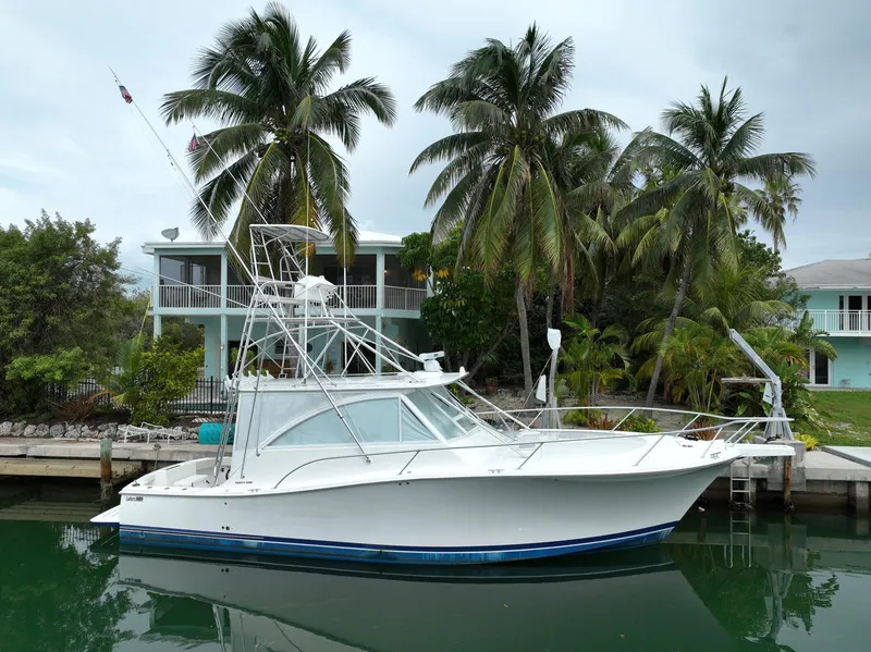 Slide: The Image of 2006 Luhrs 41 Open yacht docked near palm trees and waterfront homes. - 0