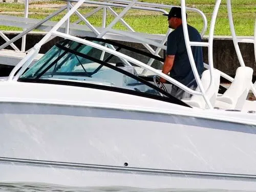 Slide: The Image of 2025 Twin Vee 240 GFX DC boat with a person at the helm, docked. - 13