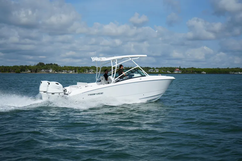 Slide: The Image of 2025 Twin Vee 240 GFX DC boat cruising on open water under a cloudy sky. - 2