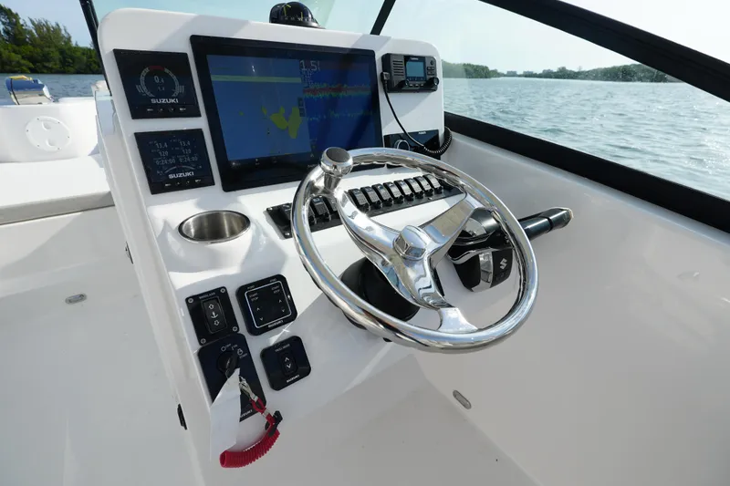 Slide: The Image of 2025 Twin Vee 240 GFX DC boat dashboard with steering wheel and navigation display. - 3