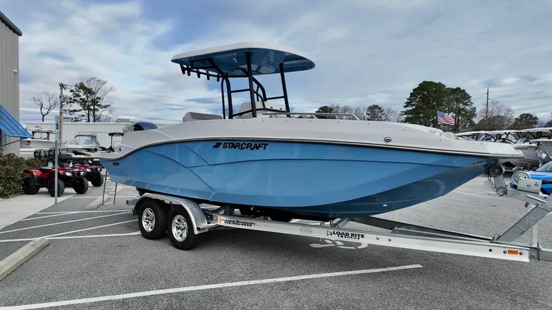 Slide: The Image of 2025 Starcraft SVX 231 OB CC boat on trailer, blue hull, parked outdoors. - 4
