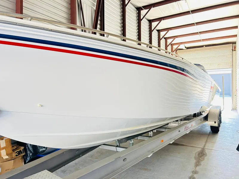 The Image of 2005 Fountain 42 Executioner boat in storage, featuring sleek white hull with red and blue stripes. - 0