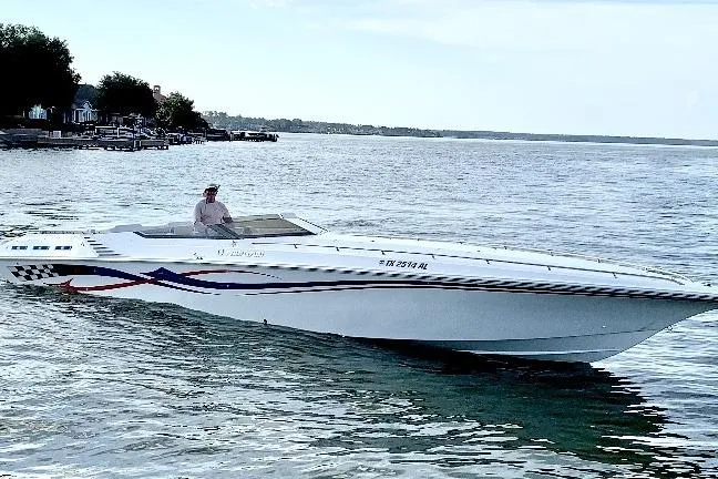 Slide: The Image of 2005 Fountain 42 Executioner speedboat cruising on a calm lake with a scenic shoreline. - 5