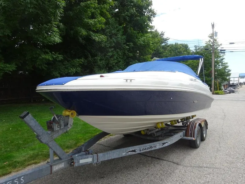 Slide: The Image of 2004 Sea Ray 220 Sundeck boat on trailer, blue and white, parked on street. - 3