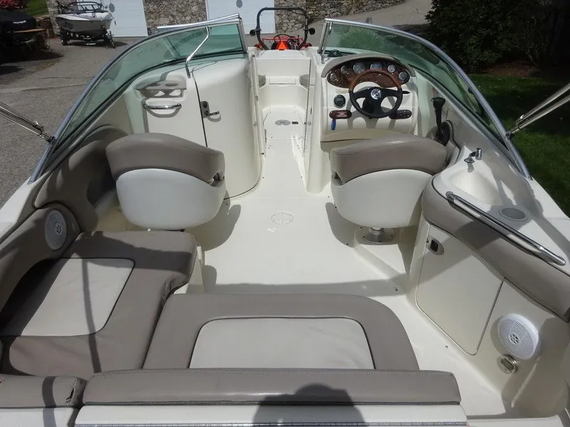 Slide: The Image of 2004 Sea Ray 220 Sundeck interior with beige seating and steering console. - 7