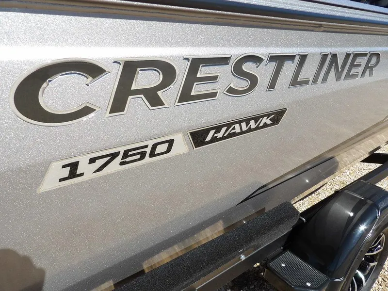 Slide: The Image of 2025 Crestliner 1750 Fish Hawk SC boat trailer with bold logo on gravel. - 43