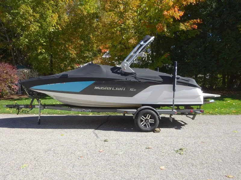 Slide: The Image of 2019 MasterCraft NXT20 boat on trailer, covered, with autumn trees in background. - 1