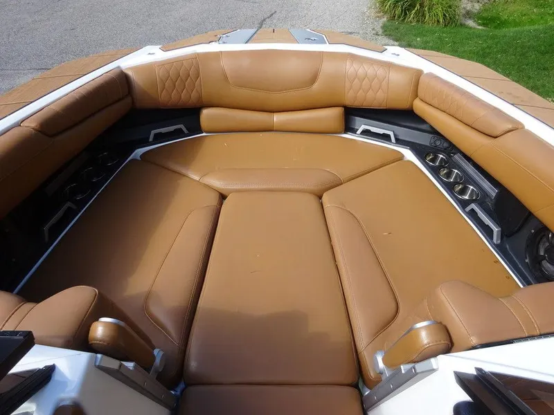 Slide: The Image of 2020 Malibu M240 boat interior with tan leather seating and cup holders. - 17