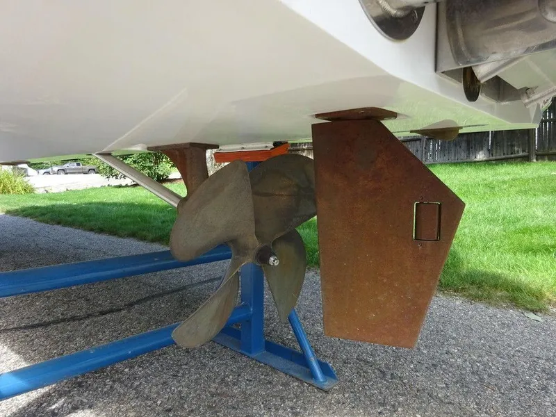 Slide: The Image of 2020 Malibu M240 boat propeller and rudder on a trailer, parked on pavement. - 19