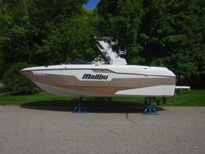 Slide: The Image of 2020 Malibu M240 boat on stands, surrounded by greenery. - 4