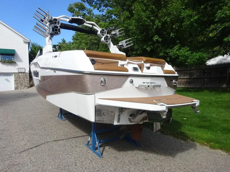 Slide: The Image of 2020 Malibu M240 boat on stands, rear view, in a driveway setting. - 6