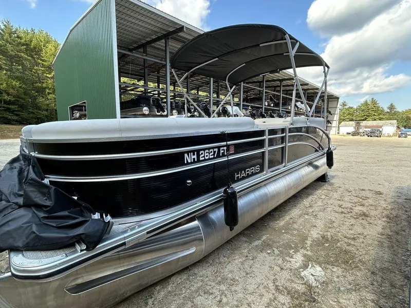 Slide: The Image of 2022 Harris Cruiser 230 pontoon boat parked outdoors near a green storage building. - 11