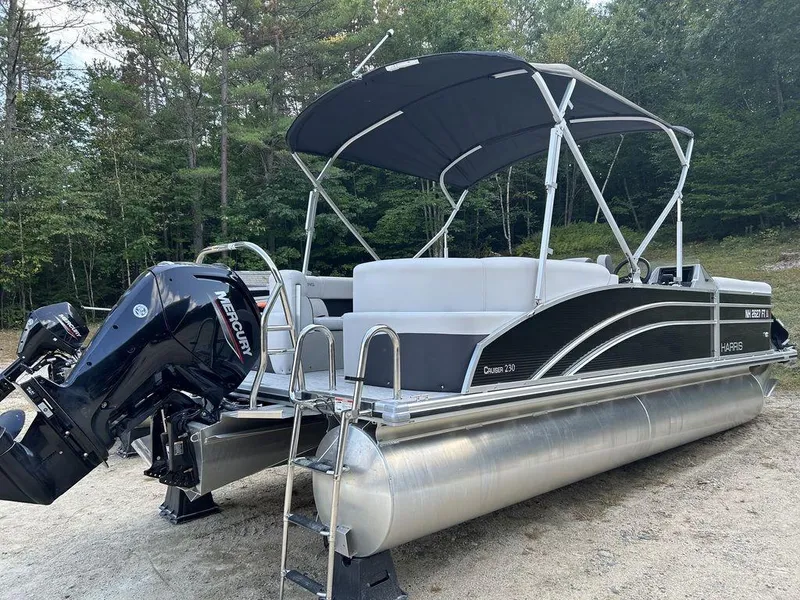 Slide: The Image of 2022 Harris Cruiser 230 pontoon boat with Mercury engine, parked on sandy shore. - 3