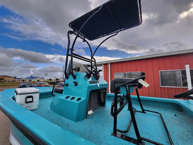 Slide: The Image of 2024 Majek Boats 21 RFL with T-top, teal deck, and console, parked outdoors. - 5