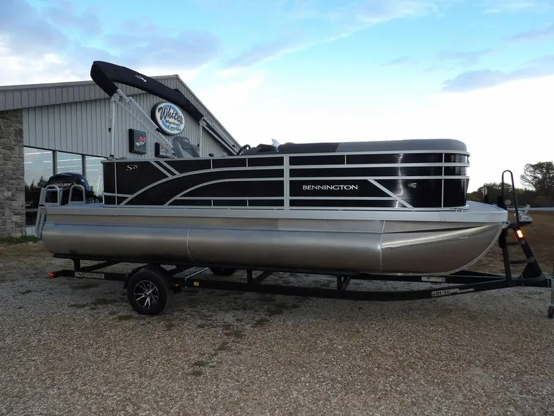 The Image of 2025 Bennington 21 SL pontoon boat on trailer, parked outside dealership. - 1