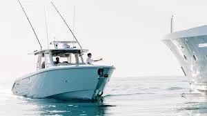 Slide: The Image of 2022 Solace 415 boat on calm water, two people onboard, clear sky. - 3