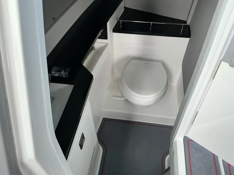 Slide: The Image of 2025 Cobalt R33 Surf boat interior with gray seating and cup holders, near water. - 13