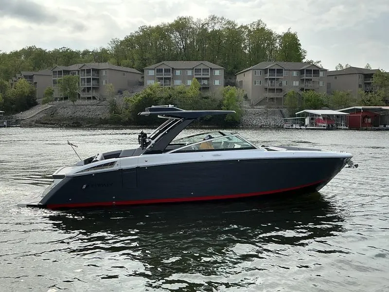 Slide: The Image of 2025 Cobalt R33 Surf boat cruising on a lake near residential buildings. - 3
