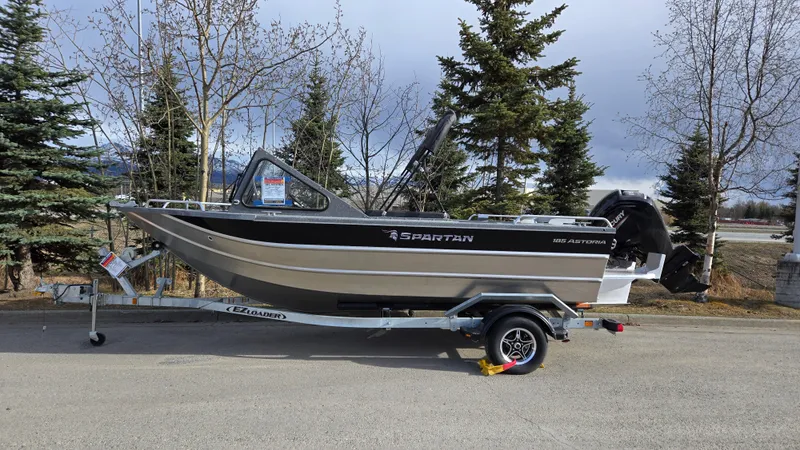 Slide: The Image of 2024 Spartan 185 Astoria boat on trailer, parked outdoors with trees in the background. - 1