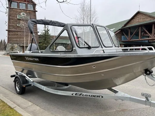 Slide: The Image of 2024 Spartan 185 Astoria boat on EZ Loader trailer, parked near rustic buildings. - 21