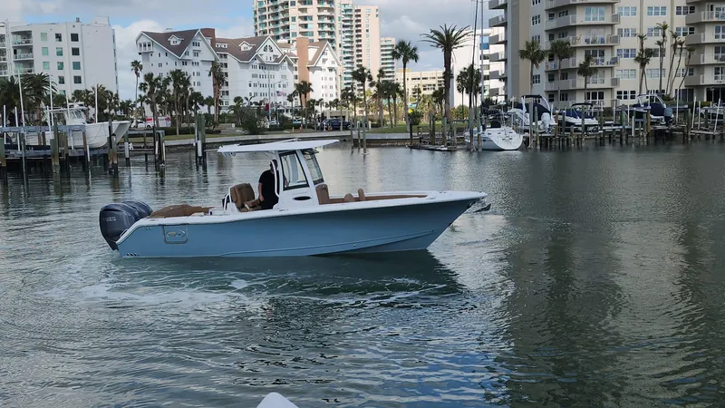 Slide: The Image of 2024 Sea Hunt Ultra 275 SE boat cruising in a marina with waterfront buildings. - 10