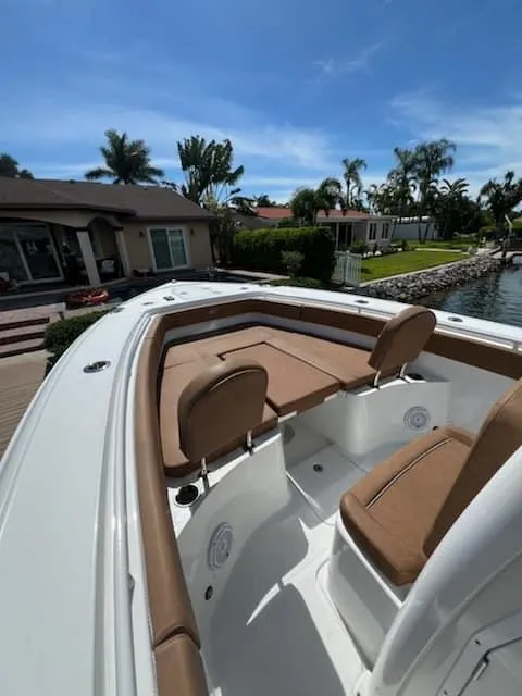 Slide: The Image of 2024 Sea Hunt Ultra 275 SE boat with brown seating, docked near waterfront homes. - 13