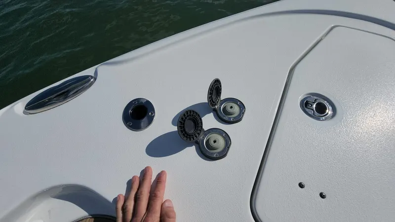 Slide: The Image of 2024 Sea Hunt Ultra 275 SE boat deck with open hatches and hand. - 32