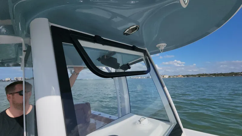 Slide: The Image of 2024 Sea Hunt Ultra 275 SE boat on water, featuring open window and clear sky. - 37