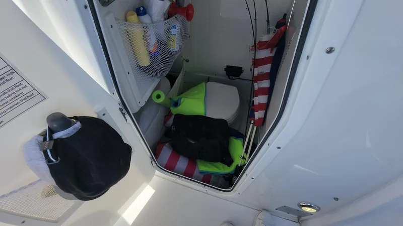 Slide: The Image of 2024 Sea Hunt Ultra 275 SE storage compartment with life jackets and supplies. - 38