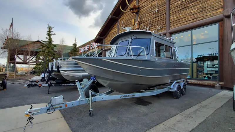 Slide: The Image of 2023 Spartan 220 Maximus boat on trailer outside a wooden building. - 1
