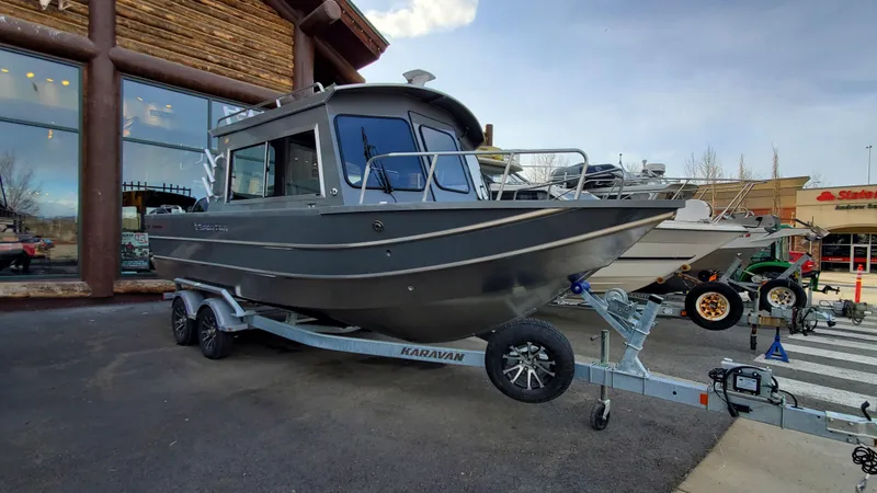 Slide: The Image of 2023 Spartan 220 Maximus boat on trailer outside a store. - 2
