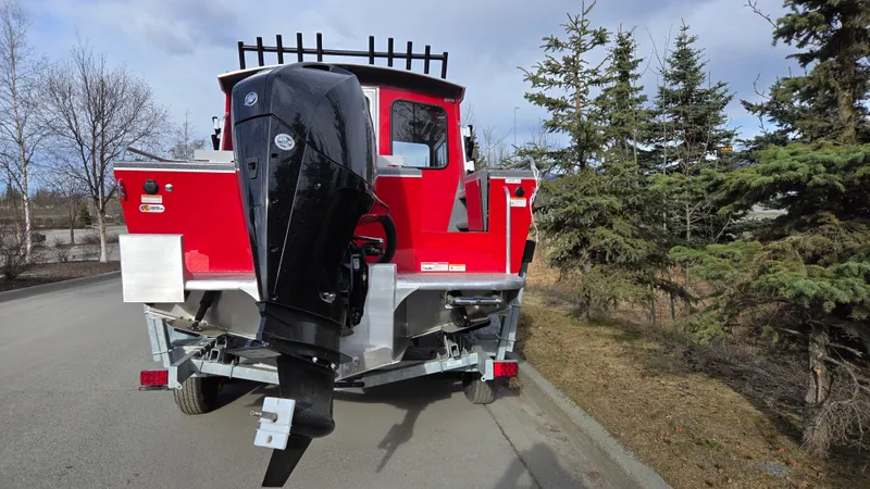 Slide: The Image of 2024 Spartan 220 Maximus boat with outboard motor on a trailer, parked near trees. - 6