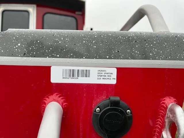Slide: The Image of 2024 Spartan 220 Maximus boat, red exterior, close-up of label and railing. - 8