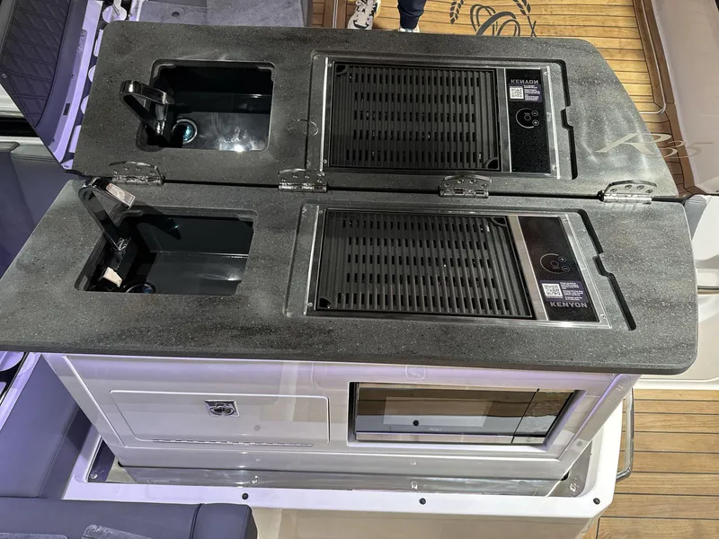 Slide: The Image of Cobalt R35 2025 boat kitchen with dual sinks and Kenyon grill on deck. - 17