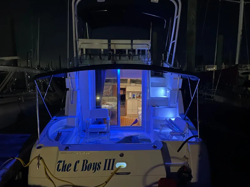 Slide: The Image of 1999 Silverton 351 Sedan Cruiser with blue interior lights at night, named "The C Boys III". - 5